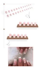 Detail of pink gradient press-on nails with white floral and rhinestone decorations