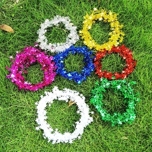 Close-up of colorful star-shaped metallic tinsel garlands in seven vibrant colors on green grass