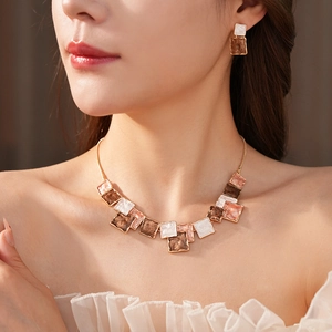 Detail of square geometric jewelry set featuring gold finish with coffee and cream enamel