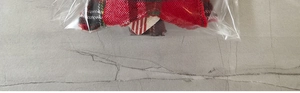 Detail of Christmas gnome plush doll in red and black plaid fabric packaging