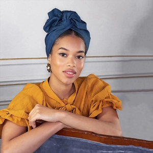 Detailansicht eines blauen Turban-Haarbands mit Falten und einem gelben Rüschenoberteil