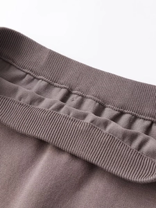 Detail eines taupefarbenen Strickkleides mit elastischem Rippbund und feiner Stoffstruktur
