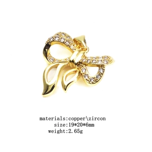 Macro view of gold bow pendant with zircon inlays and detailed sizing dimensions
