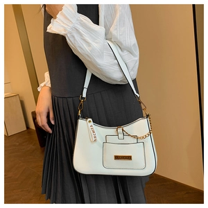 Close-up of white crossbody bag with golden chain and Parchita metallic logo plate