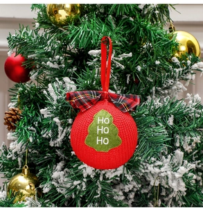 Close-up of red knit Christmas ball with HO HO HO embroidery and plaid bow on tree