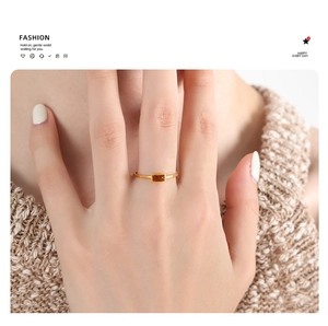 Close-up of a gold titanium ring featuring a rectangular brown gemstone on a hand