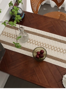 Close-up of beige woven table runner with brown geometric patterns and tassel detail
