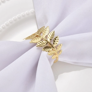 Elegant gold metal leaf napkin ring on white fabric in a clean professional setting