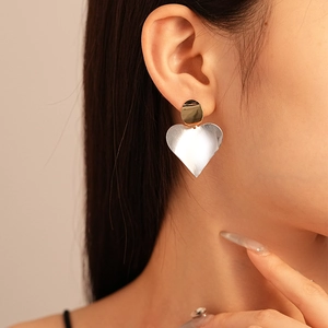 Close-up of model wearing two-tone gold and silver heart drop earrings for women