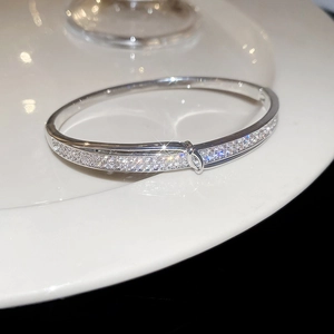 Détail macro d'un jonc argenté avec micro-pavage de zircone et fermoir géométrique