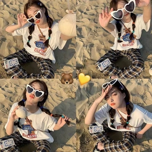 Detail view of heart-shaped sunglasses paired with a cartoon bear graphic t-shirt