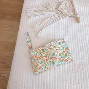 Macro view of floral cotton phone bag with wristlet strap on a quilted background