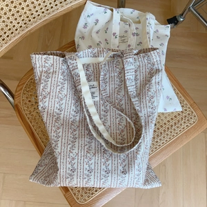 Detail of floral canvas tote bags with vintage stripes and white woven tags on a chair