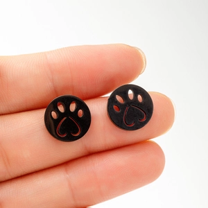 Macro shot of black cat paw earrings with heart cutout held between fingers