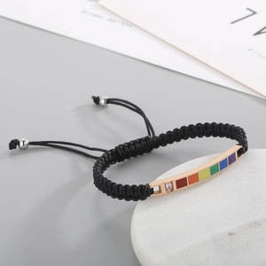 Close-up of rainbow curved metal bar on black woven bracelet with pink crystal detail