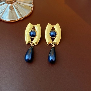 Detailed macro of vintage gold flower earrings with deep blue beads on leather