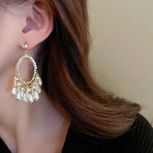 Gros plan de boucles d'oreilles ovales dorées avec perles blanches sur le modèle