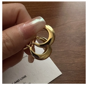 Detailed view of gold crescent U-shaped sterling silver hoop earrings held by hand