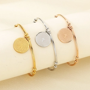 Detail of cross charm with Spanish Lord's Prayer engraving on stainless steel bracelets
