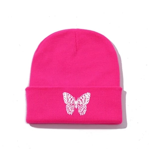 Detailed view of white butterfly embroidery on a hot pink knitted beanie hat