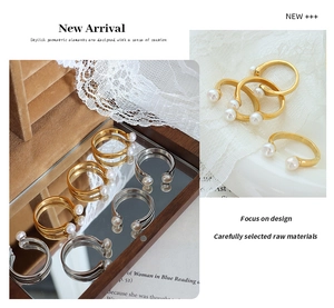 Detailed view of baroque pearl gold-plated U-shaped open rings on vintage lace and book