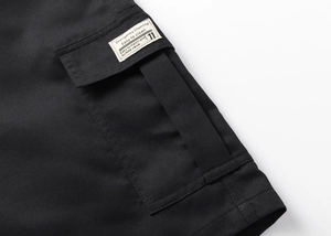 Close-up of durable black cotton twill fabric and side cargo pocket with label detail