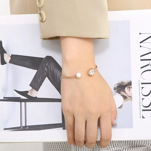 Detail of rose gold open cuff bracelet with heart rhinestone and white pearl accent
