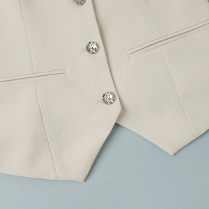Detail of off-white vest showing twill fabric texture and silver hammered metal buttons