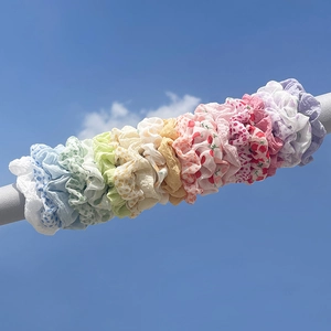 Close-up of assorted floral and polka dot scrunchies on a rod under a blue sky