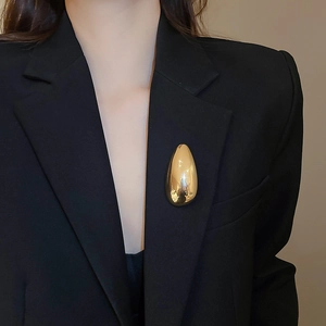 Golden teardrop brooch with mirror finish shown on a black suit jacket lapel