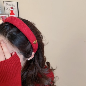 Detail of red velvet headband with golden heart ornament and thick winter fabric texture