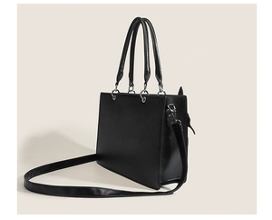 Detail of a structured black faux leather tote bag with dual handles and long shoulder strap