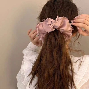 Detail of elegant dusty pink satin scrunchie styled on a low ponytail for women