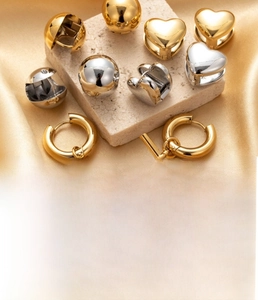 Close-up of heart and sphere titanium steel earrings in gold and silver finishes