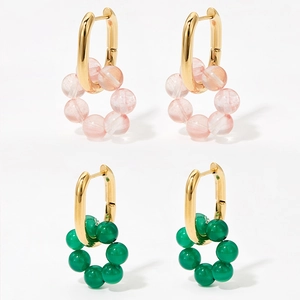 Golden earrings with hanging pink and green natural stone bead hoops on white background