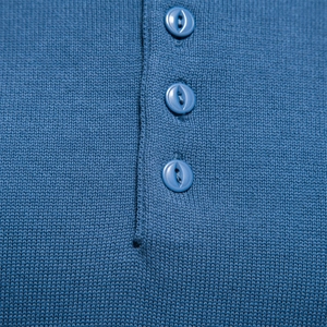 Macro shot of dark blue knit sweater placket with three matching resin buttons