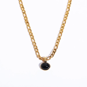 Detail of 14K gold Figaro chain featuring a round black natural stone pendant on white background