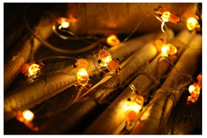 Macro shot of reindeer LED string light with warm yellow glow on rustic paper background