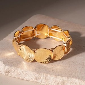 Dettaglio ravvicinato dei dischi dorati con trama martellata del bracciale elastico
