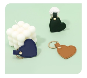 Detailed view of heart-shaped leather keychains in green, navy, and brown colors
