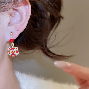 Gros plan de boucles d'oreilles lion chinois avec perles rouges sur un mannequin