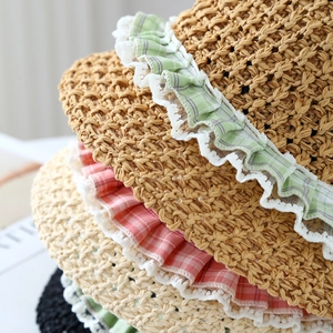 Detailed macro view of woven straw hats featuring lace edges and checkered fabric decor