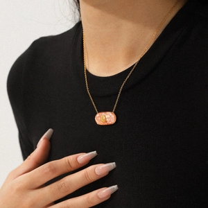 Golden stainless steel oval necklace with pink marble shell inlay worn by a model