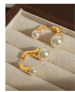 Dettaglio di orecchini vintage in oro con doppia perla in un portagioie in velluto beige