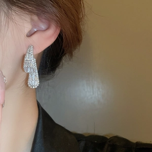 Close-up of a model wearing square hollow silver earrings with sparkling zircon stones