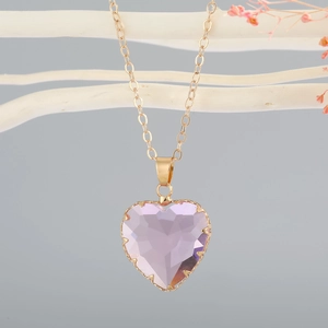Macro detail of a heart-shaped purple crystal pendant with a sleek gold chain