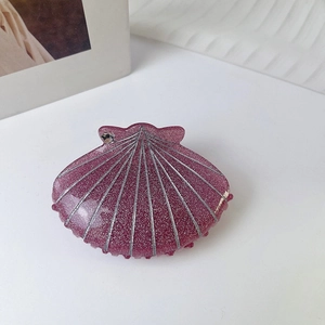 Detailed close-up of dark pink shell hair claw with sparkling glitter and crystal accent
