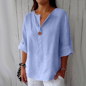 Dettaglio camicia in lino azzurro con scollo a V e un grande bottone decorativo
