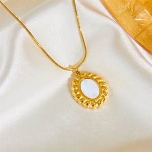 Macro shot of gold oval pendant with mother of pearl inlay and snake chain detail