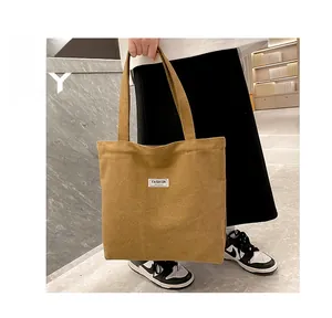 Close-up of thick mustard corduroy tote bag featuring a white Fashion label detail